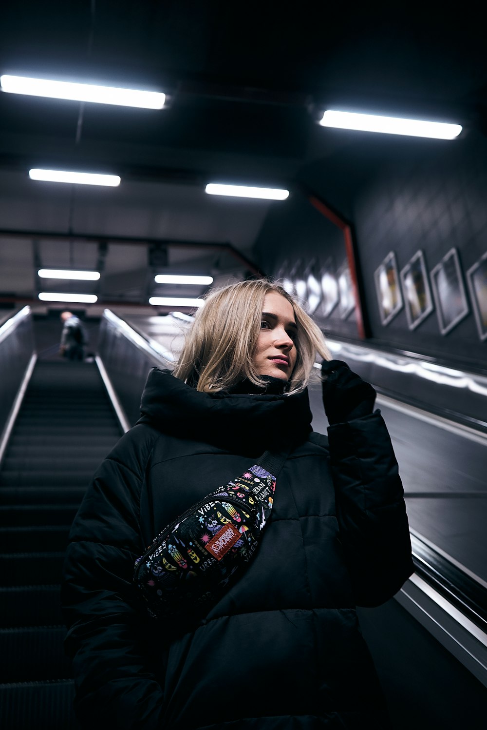 woman wears black jacket riding escalator