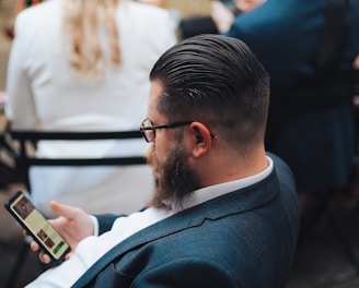 a man sitting in a chair looking at his cell phone