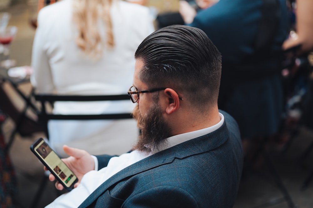 a man sitting in a chair looking at his cell phone