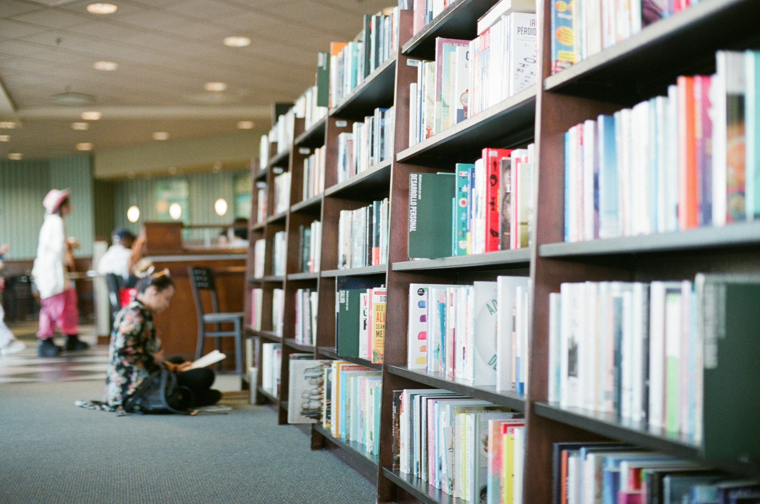 woman reading book in front of bookshelves