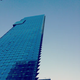 High-angle shot of a gleaming modern skyscraper under a clear blue sky.