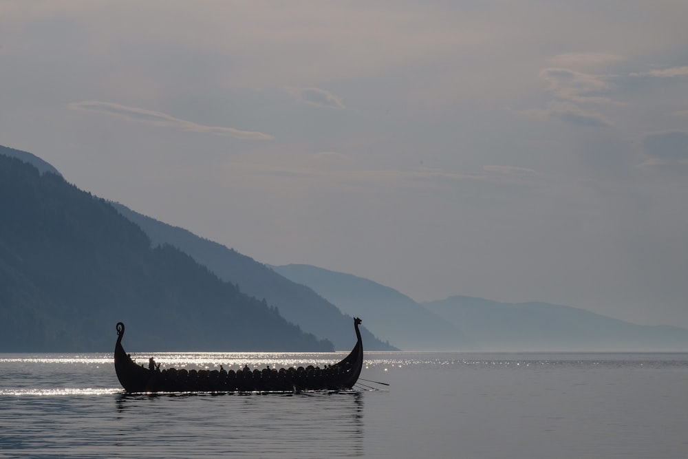 a long boat with two people in it on a lake