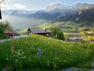 A panoramic view of a taxi waiting outside a cozy guesthouse in a Himachal village.