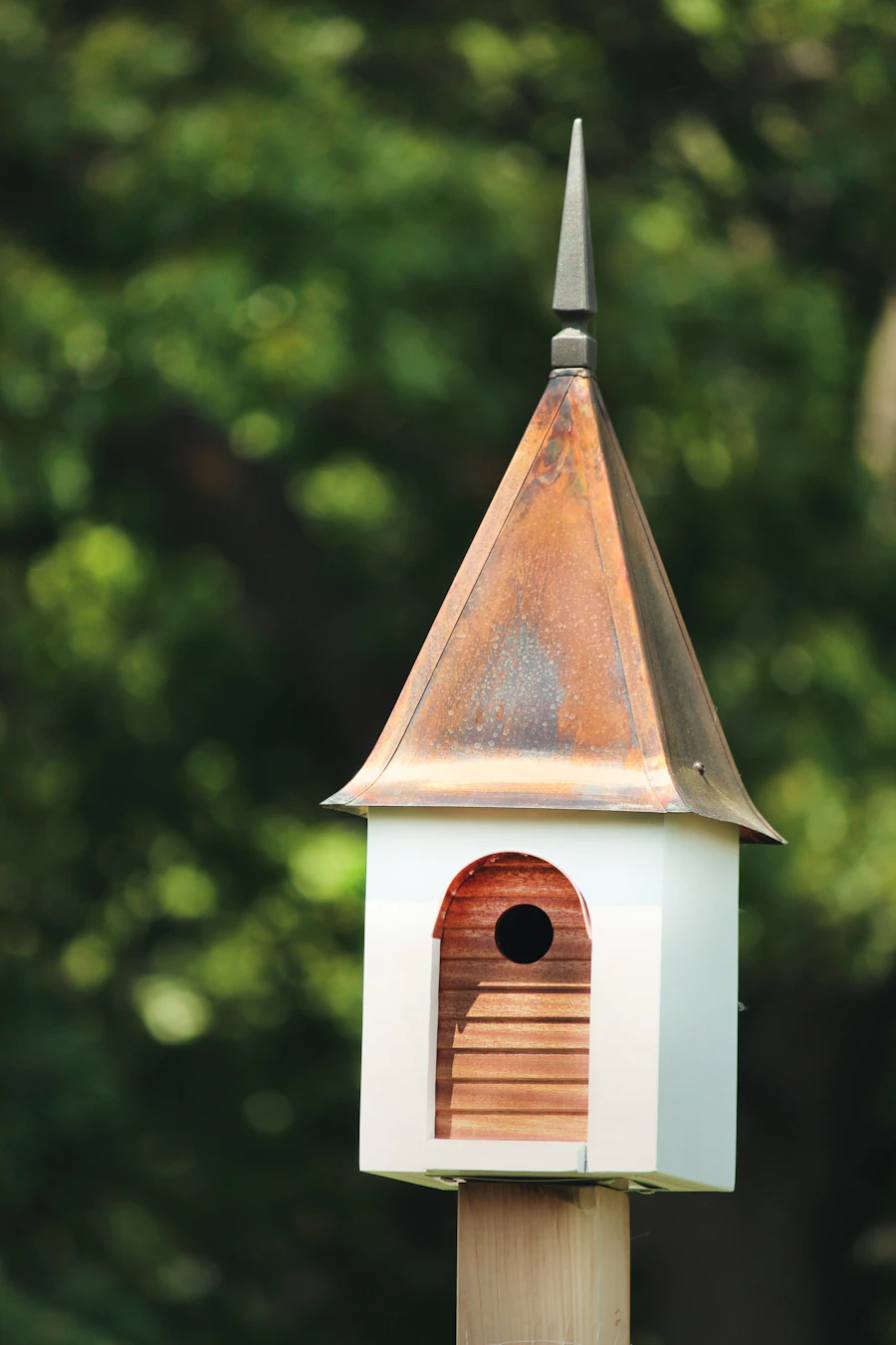 A white birdhouse with a copper roof