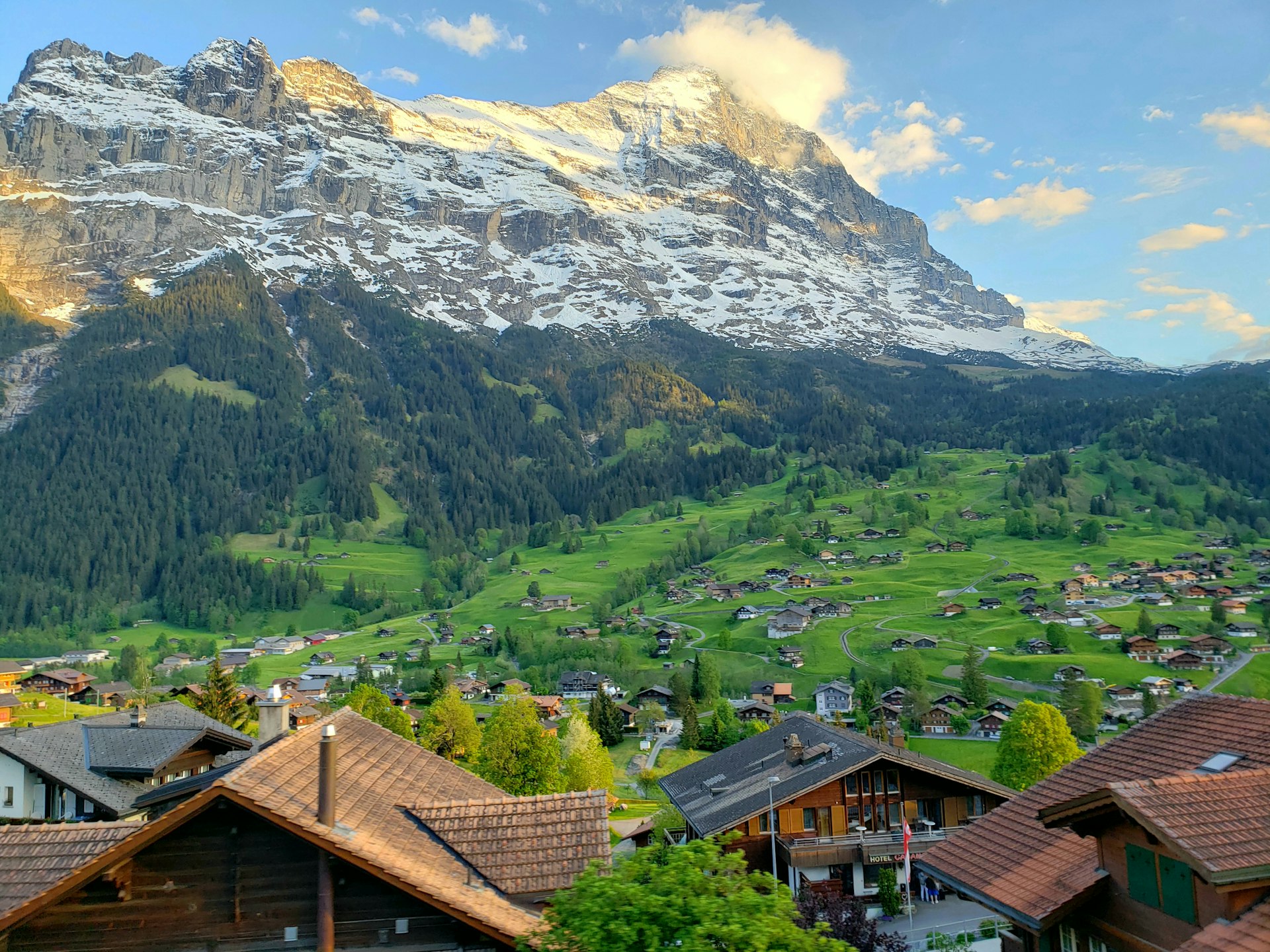 Grindelwald village in a green alpine valley beneath the snow-dusted north face of the Eiger, Switzerland