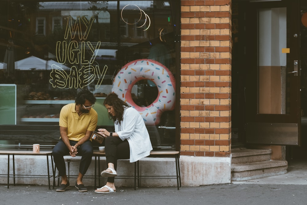man and woman sitting in front of store