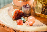 Close-up of colorful quartz crystals arranged on a wooden table, glowing under natural light.