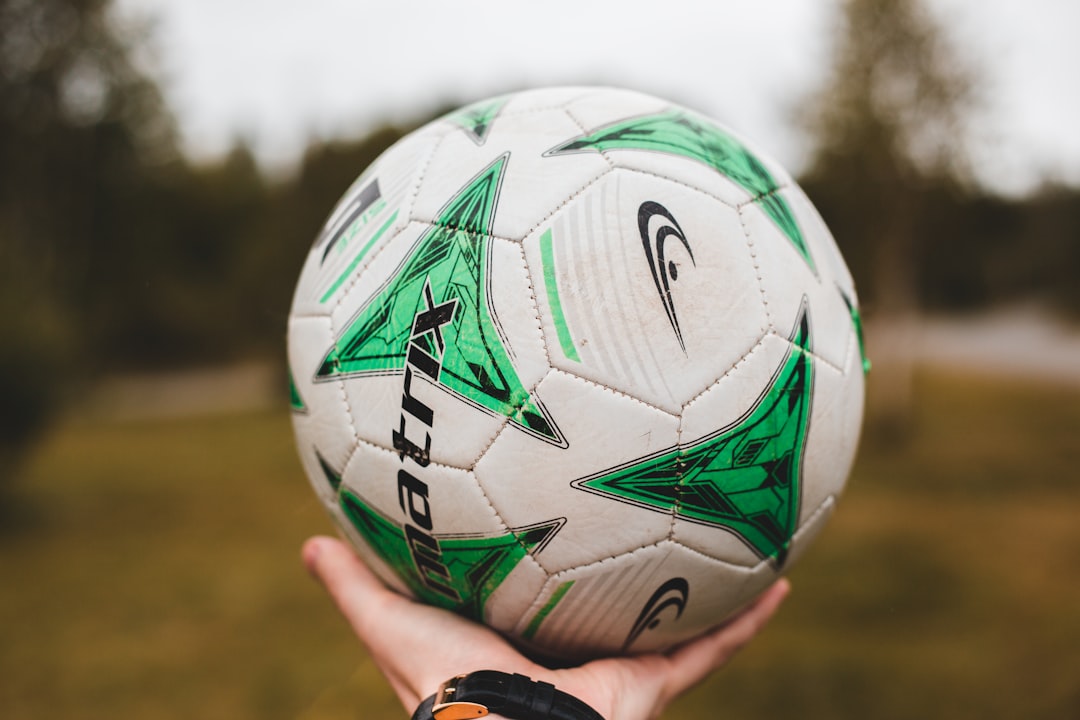 person holding white and multicolored soccer ball