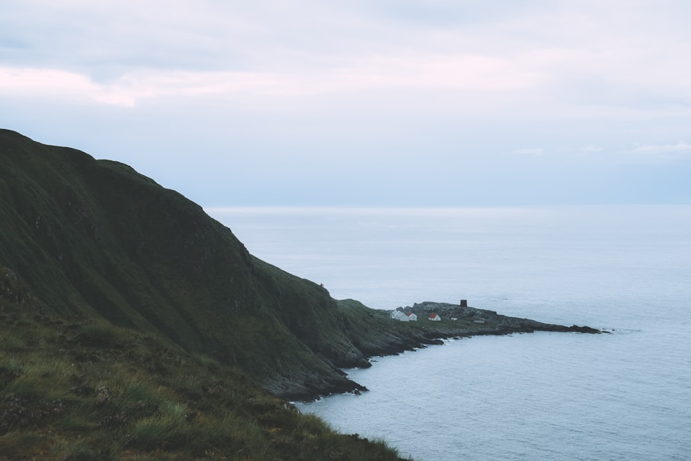 a hill with a house on top of it next to the ocean