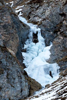 Frozen waterfall cascading down a rugged ice cliff.