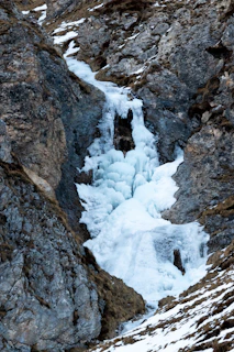 Frozen waterfall cascading down a rugged ice cliff.