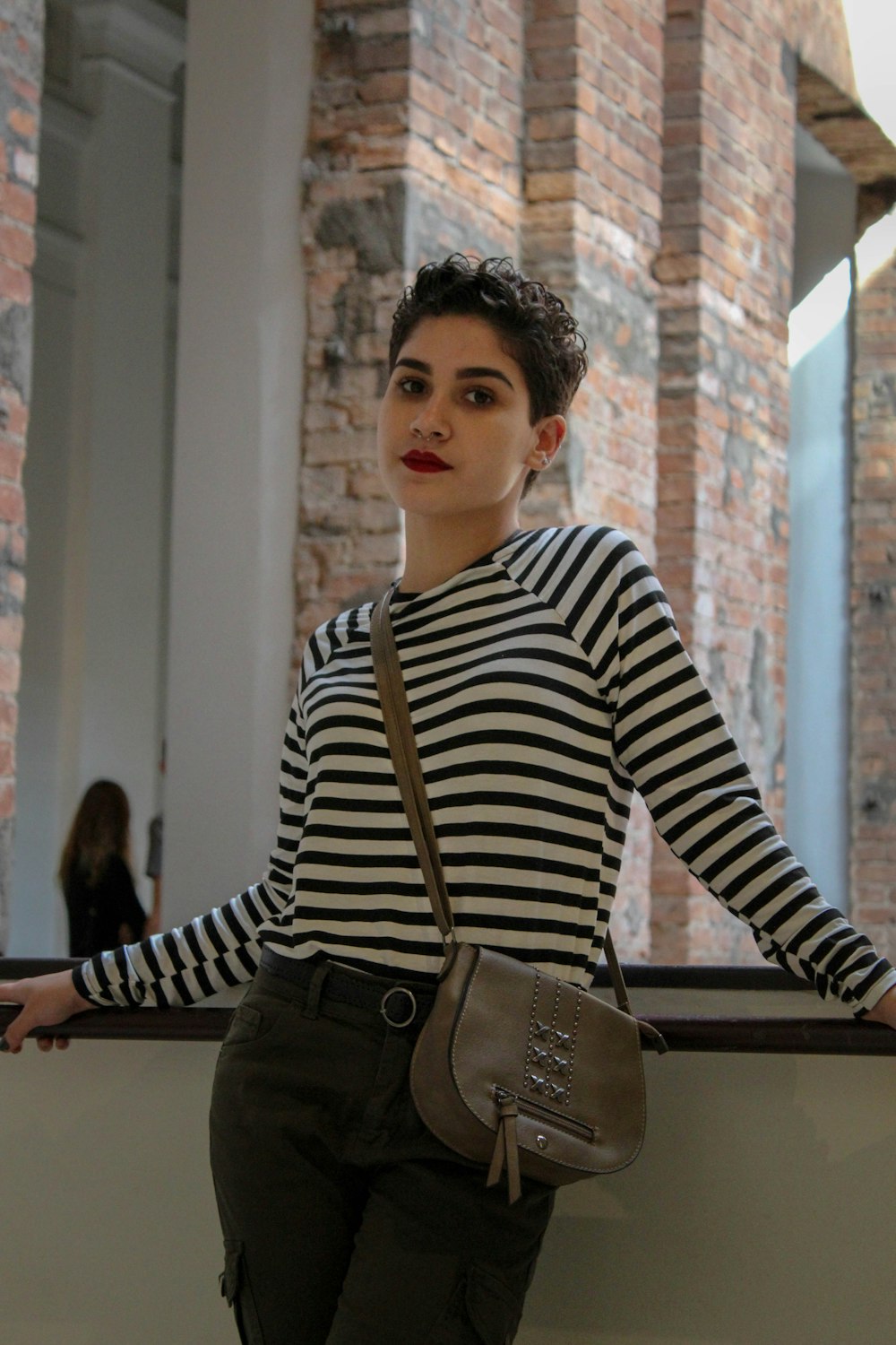 woman in black and white striped top beside window