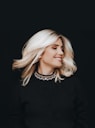 a woman with blonde hair wearing a black top
