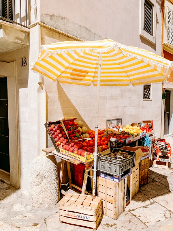 A yellow and white umbrella and some crates of fruit