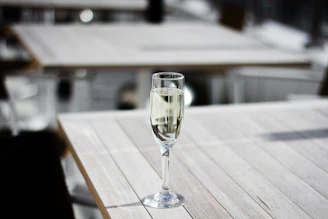 A sunlit table set with a delicate glass of champagne and an open journal, bathed in warm morning light.