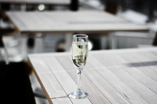 A sunlit table set with a delicate glass of champagne and an open journal, bathed in warm morning light.