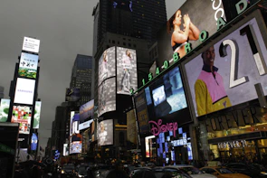 Close-up of a colorful digital billboard showcasing a brand campaign at a busy urban railway hub.