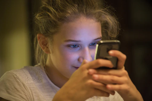 A candid photo of a young person intensely scrolling through social media on their phone.