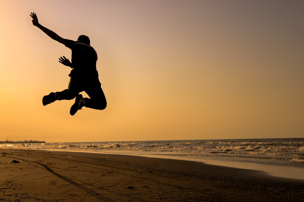 silhouette of person jumping on seashore