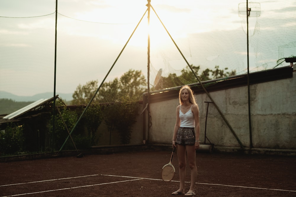 woman holding white tennis racket while standing in field