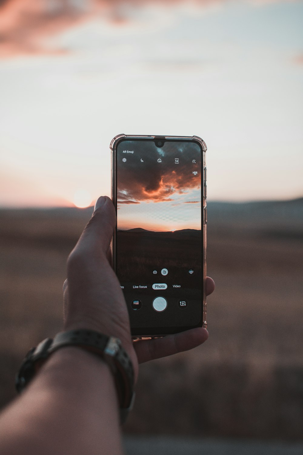person about to capture sunset on phone