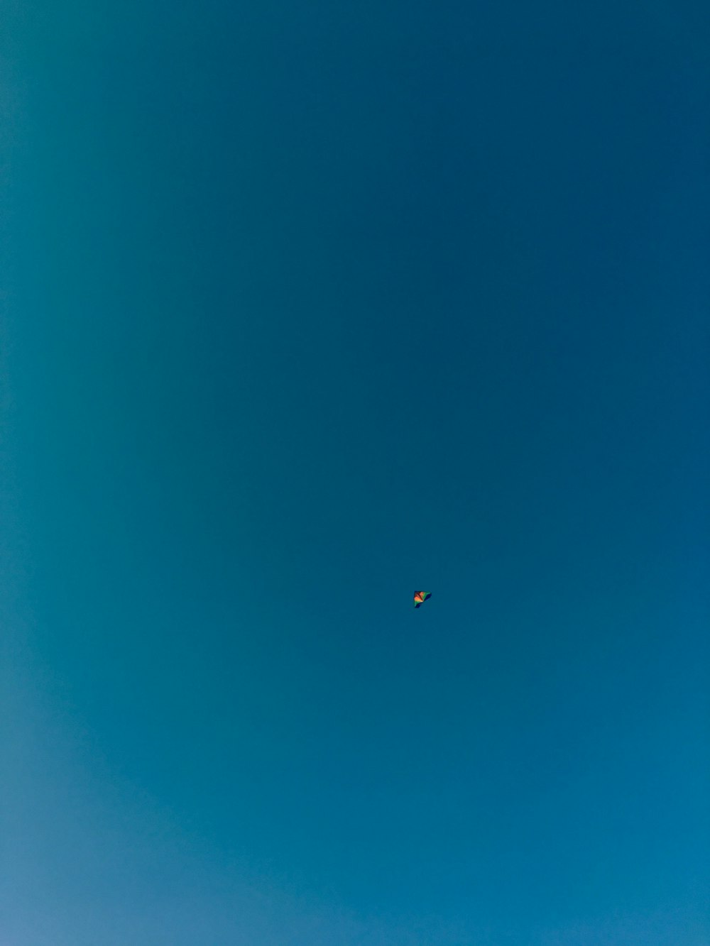 a group of people flying kites in a blue sky