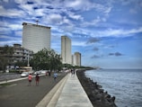 people walking on side walk beside beach