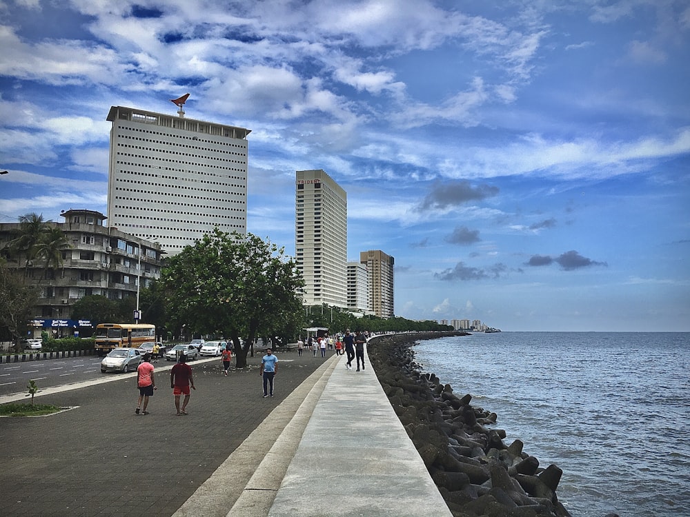 people walking on side walk beside beach