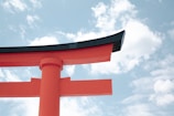 A vibrant red torii gate standing tall against a clear blue sky in a serene Japanese shrine