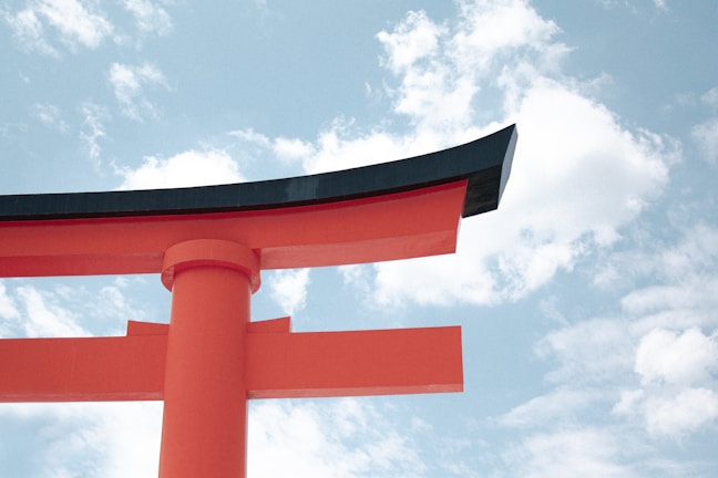 A vibrant red torii gate standing tall against a clear blue sky in a serene Japanese shrine