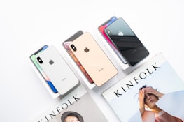 Several iPhones in different colors are displayed on their boxes beside a Kinfolk magazine featuring a person on the cover.