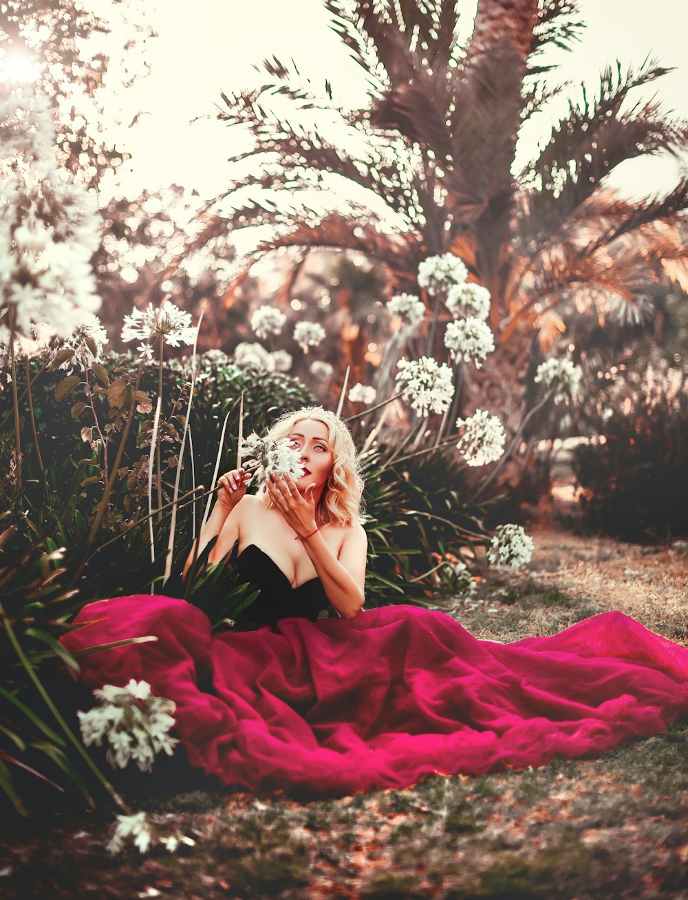 woman sitting beside white petaled flowers at daytime