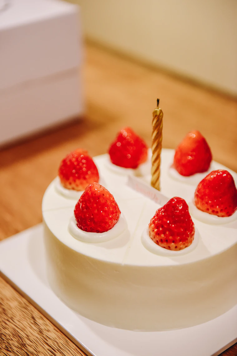 White iced layered birthday cake with strawberries