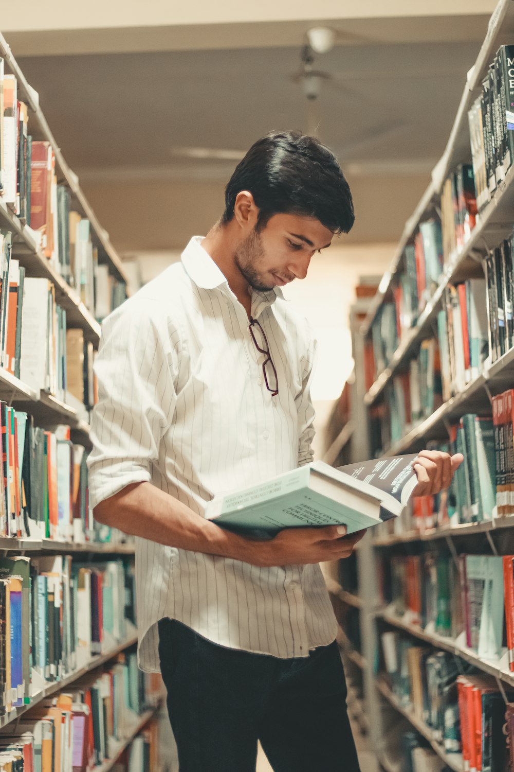 Mann liest in der Bibliothek