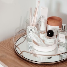a glass tray with a variety of beauty products on it