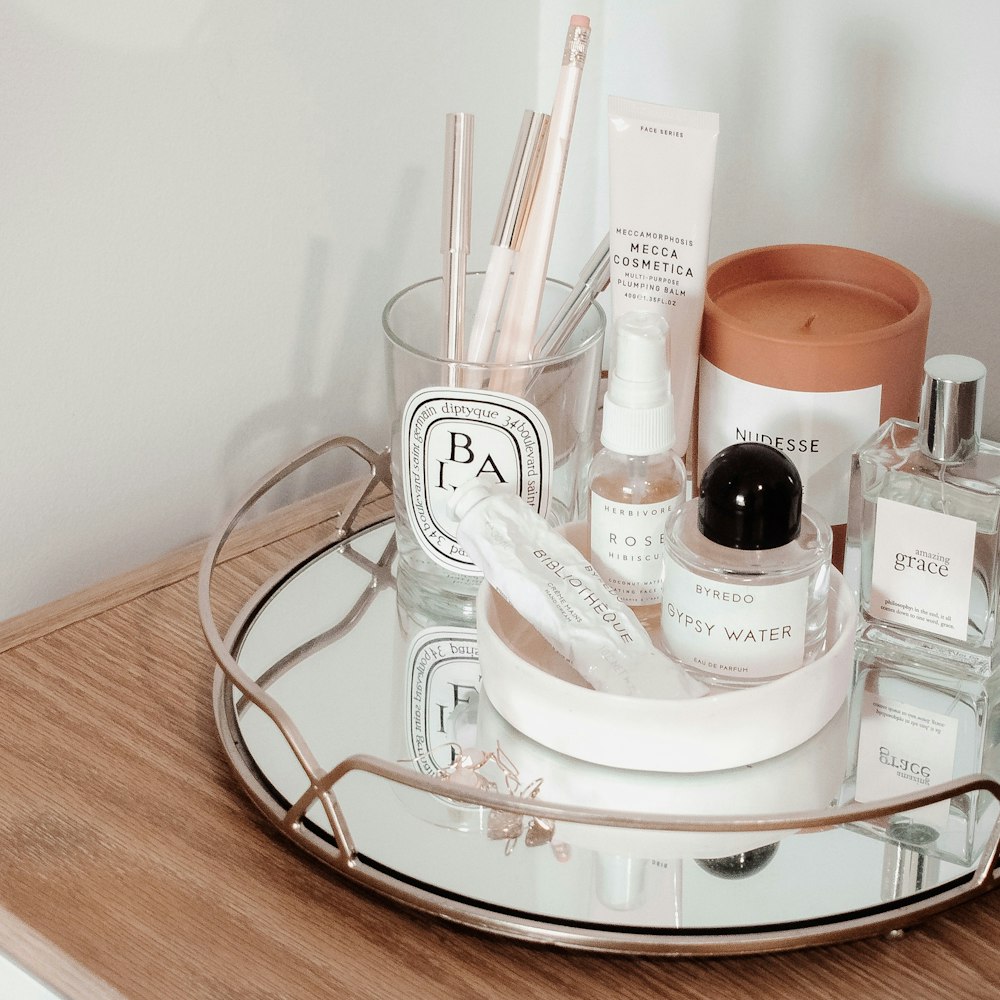 a glass tray with a variety of beauty products on it
