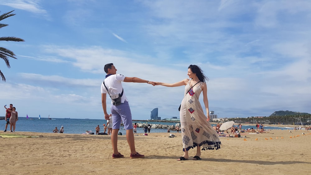 man and woman holding hands on beach