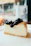 Close-up of a creamy cheesecake slice with a golden crust on a rustic plate.