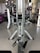 A gym setting with workout equipment including weights and a pulling mechanism. There are various weightlifting machines and plates organized in the background.