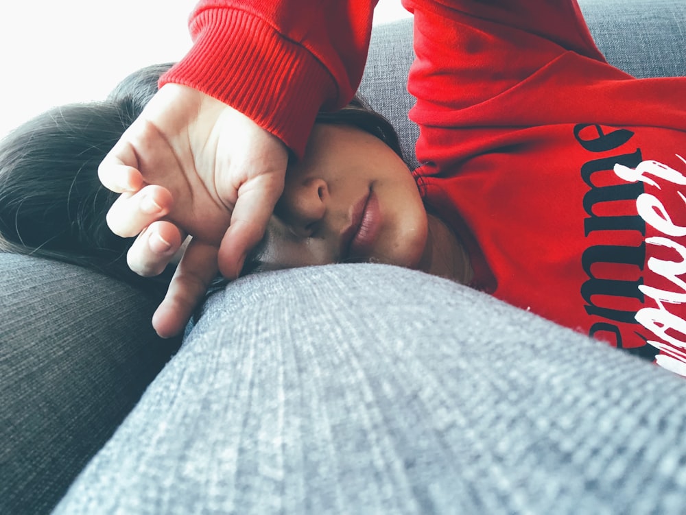 femme portant un chandail rouge couché sur une surface grise