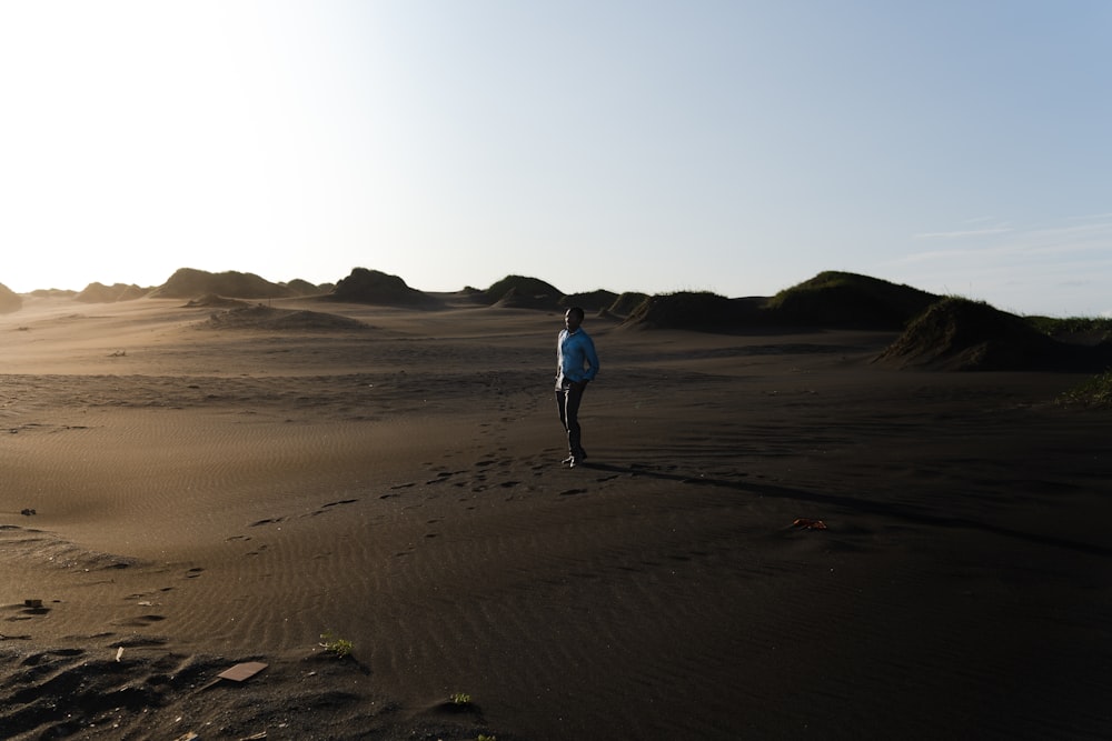 person wearing blue shirt standing on grey sand during daytime