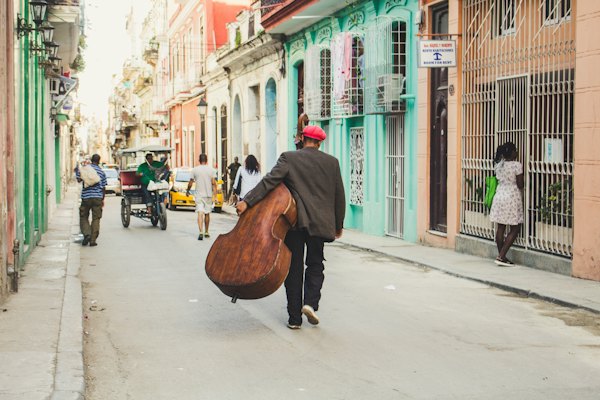 Man carrying stringed instrument while walking the pavement during daytime — Havana, Cuba