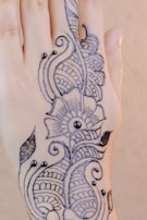 Mehndi artist focused while creating delicate paisley patterns on a bride’s forearm during a wedding ceremony.