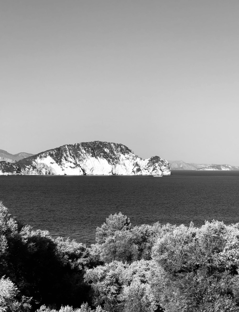 grayscale photography of calm water and mountain