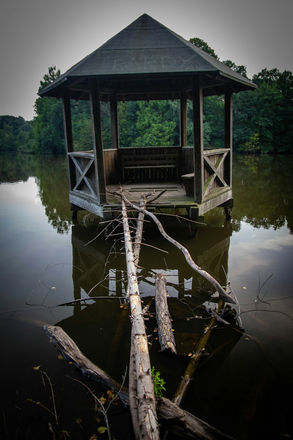 grauer Holzpavillon auf ruhigem Wasser