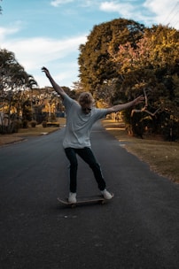 A longboard cruising smoothly down a tree-lined suburban street on a sunny day.