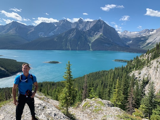 man standing on cliff with mountain view in Kananaskis Improvement District Canada