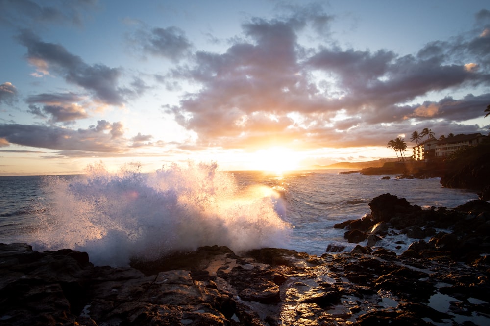 photography of ocean waves crashing on rock during sunset