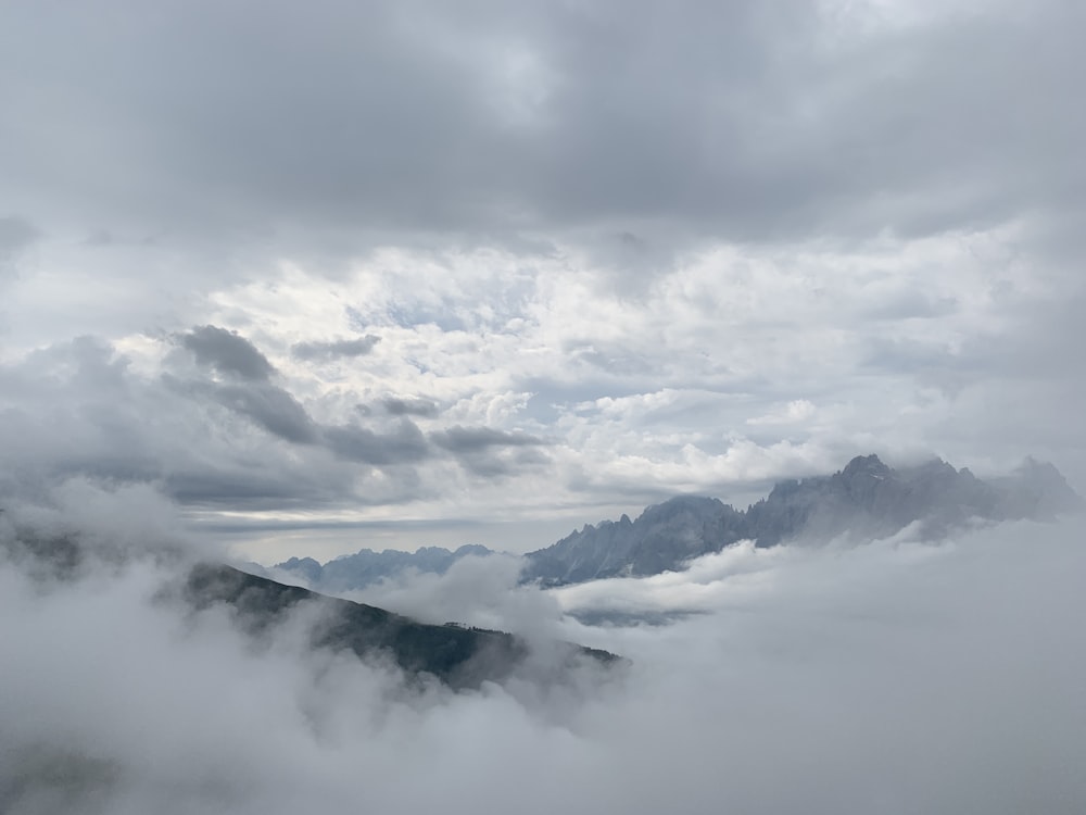 Photographie d’une chaîne de montagnes recouverte de nuages blancs pendant la journée