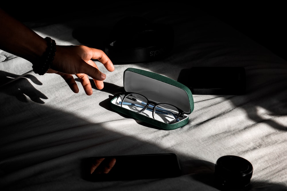 person about to hold black-framed eyeglasses in case